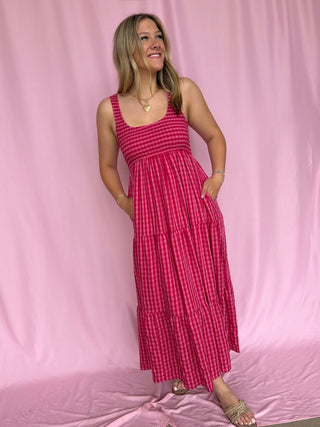 Woman wearing a red checkered dress against a pink background