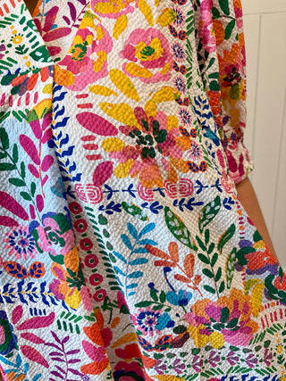 Close-up of a colorful floral quilt with vibrant patterns on a white background.