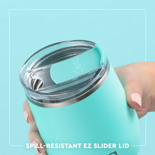 Turquoise tumbler with a spill-resistant EZ Slider lid held by a hand against a light blue background.