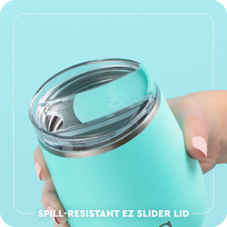 Turquoise tumbler with a spill-resistant EZ slider lid held by a hand against a light blue background.