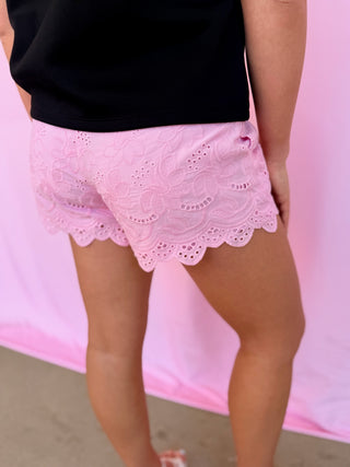 Person wearing pink lace shorts with a blurred background