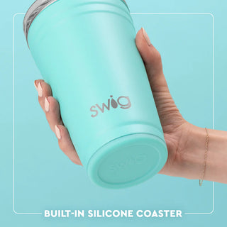 Hand holding a turquoise Swig tumbler with a light blue background