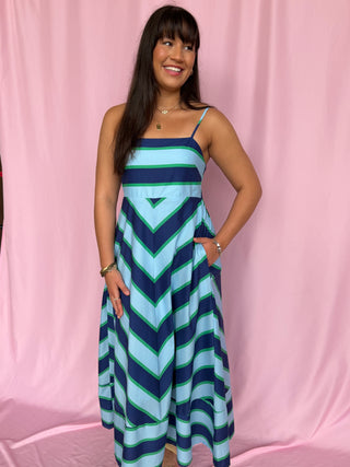 Woman wearing a blue and green striped dress against a pink background