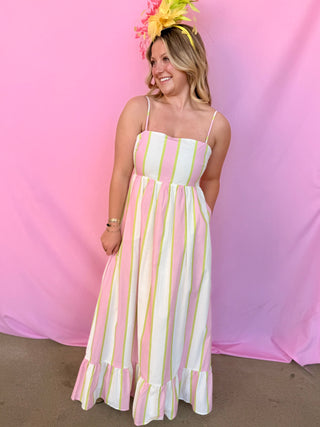 Woman in a striped dress with a colorful headband against a pink background