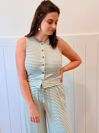 Woman wearing a striped dress with buttons against a light-colored wall.