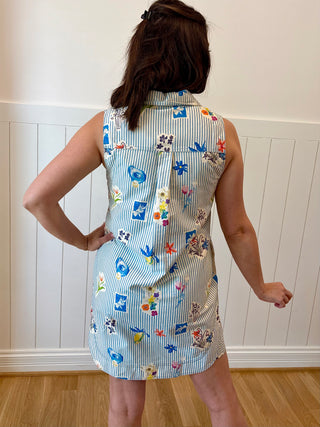 Person wearing a sleeveless dress with colorful pattern against a white paneled wall.