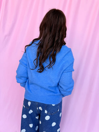 girl wearing blue sweater on a pink background