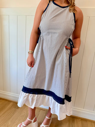 Woman wearing a white and blue striped dress with a white wall background