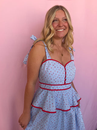 Woman wearing a blue dress with red trim against a pink background