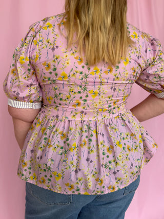 Person wearing a floral blouse with a pink background