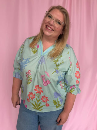 Woman wearing a floral blouse against a pink background
