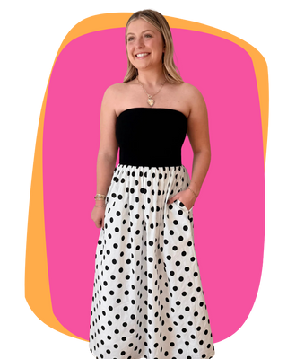 Woman wearing a black strapless top and polka dot skirt against a colorful background