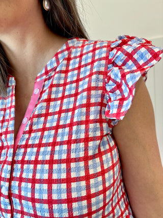 Red and blue checkered shirt with ruffled sleeves worn by a person.