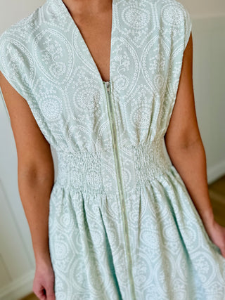 Light green patterned dress with a zipper detail on a neutral background