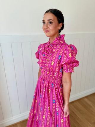 Woman wearing a pink dress with a white paneled wall background