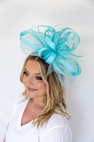 Woman wearing a large turquoise decorative headpiece against a white background