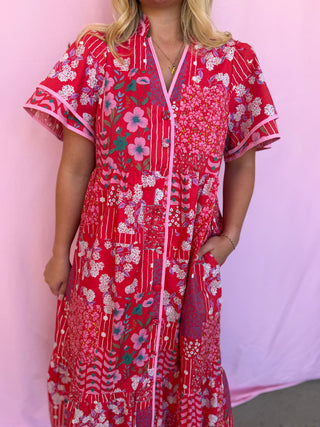 Person wearing a red floral dress against a pink background