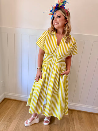 Woman wearing a yellow striped dress with a decorative headpiece indoors.