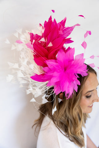 Woman wearing a vibrant pink feathered headpiece against a white background