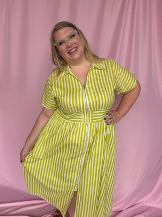 Woman wearing a yellow and white striped dress against a pink curtain background