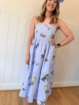 Woman wearing a floral dress indoors with a white wall background