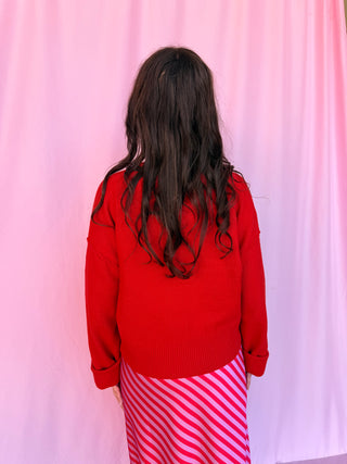 girl wearing a red sweater on a pink background