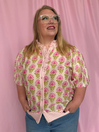 Person wearing a floral blouse with a pink background