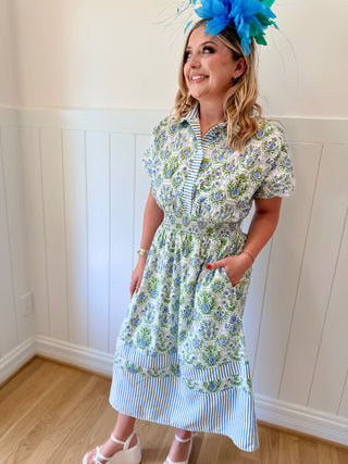 Woman wearing a floral dress with a blue flower headpiece indoors.