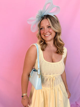 Woman wearing a yellow dress and decorative headpiece against a pink background