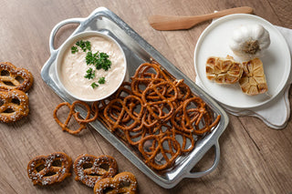 Tray of pretzels with a bowl of dip on a wooden surface