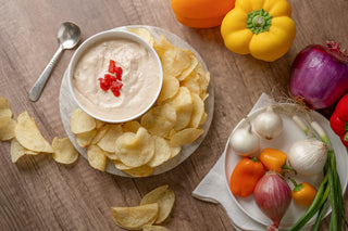 Dip with chips and fresh vegetables on a wooden table