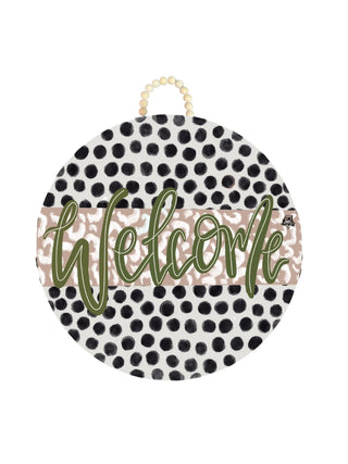 Round decorative sign with 'Welcome' text on a polka dot pattern