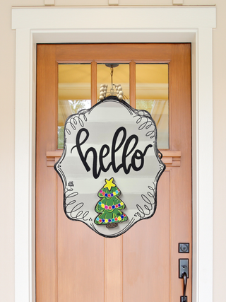 Decorative door hanger with 'hello' and Christmas tree design on a wooden door.