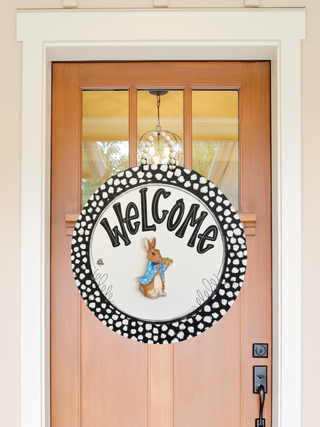 Decorative door sign with 'Welcome' and a character on a wooden door.