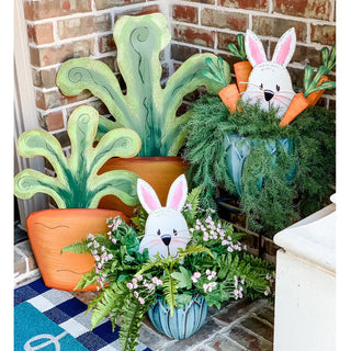 Decorative Easter planters with bunny faces and carrots on a brick surface.