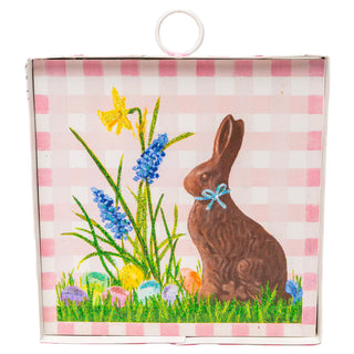 Easter-themed packaging with a chocolate bunny and flowers on a pink checkered background