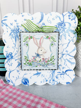 Decorative frame with a bunny illustration on a table with a checkered cloth.