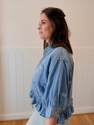 Woman wearing a denim jacket in a room with a neutral wall.