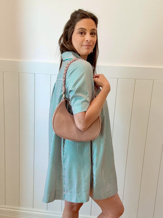Woman holding a beige handbag against a white paneled wall