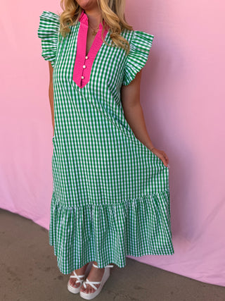 Person wearing a green and white checkered dress with a pink collar against a pink background