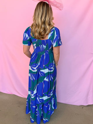 Woman wearing a blue floral dress against a pink background