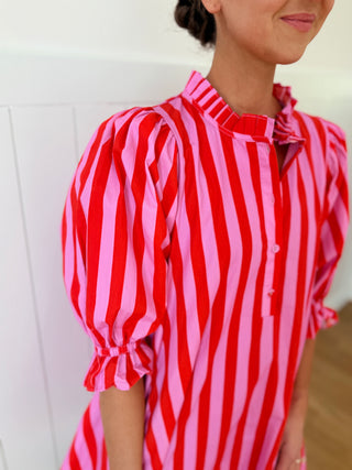 Person wearing a red and pink striped dress against a white background