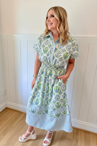 Woman wearing a floral dress with a blue flower headpiece indoors.