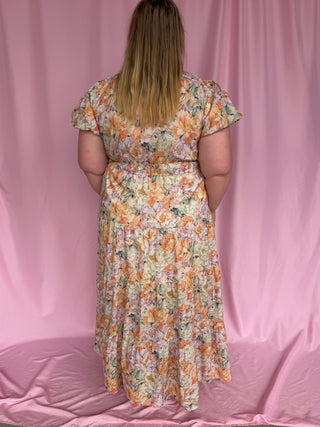Person wearing a floral dress against a pink curtain background