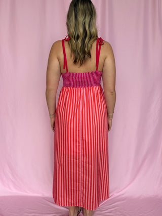 Woman wearing a red and white striped dress against a pink background