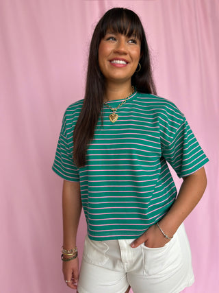 Woman wearing a green striped shirt against a pink background