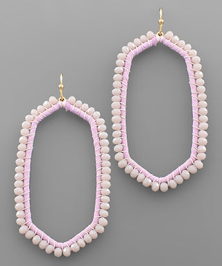 Pair of beaded earrings with pink and white beads on a gray background