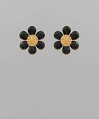 Black flower-shaped earrings with gold centers on a gray background