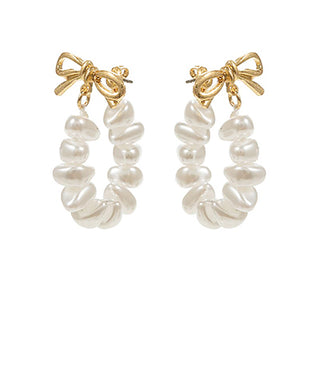 Pearl hoop earrings with gold bows on a white background