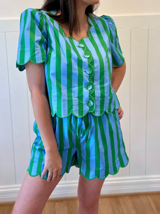 Person wearing a green and blue striped outfit against a white paneled wall.